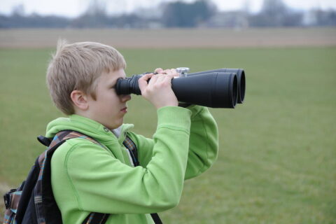Junge mit zu großem Fernglas als Negativbeispiel für Kinderfernglas