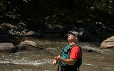 Angler im Fluss mit Fernglas, konzentriert auf die Umgebung