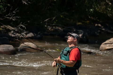 Angler im Fluss mit Fernglas, konzentriert auf die Umgebung